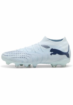 Botas de fútbol Puma blancas con logo azul marino, parte superior texturizada, collarín en el tobillo y tacos moldeados en la suela.