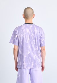 Purpura acs t-krekls ar tie-dye rakstu un melnu apkakli, īsām piedurknēm un brīvu piegriezumu. Viegls un elpojošs materiāls.