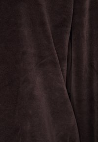 Tessuto morbido di un marrone scuro con una texture vellutata e soffice, caratterizzato da leggeri drappeggi e linee fluide e lisce. Design minimalista.