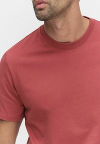 Rød bomulds t-shirt med klassisk rund halsudskæring og korte ærmer, med en glat tekstur og uden synlige mønstre eller detaljer.