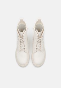 Białe skórzane botki za kostkę z sznurówkami i zaokrąglonym noskiem, z zamkami błyskawicznymi po bokach oraz teksturowanymi gumowymi podeszwami.