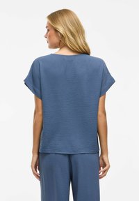 Top blu textured con una vestibilità morbida, maniche corte e scollatura rotonda. Presenta delicati motivi a onda e un orlo dritto.