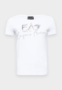 Camiseta de algodón blanca con mangas cortas, presenta un logo "EA7" brillante y texto en plata metálica, adornada con rayas coloridas y escritura.