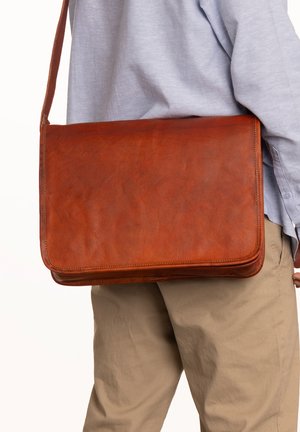 Pruun nahk messenger kott, millel on sile tekstuur, klappkinnitus ja pikk reguleeritav rihm. Kompaktne ristkülikukujuline vorm.