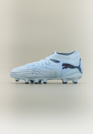 Bílá fotbalová kopačka se šněrováním, texturovaným svrškem pro lepší úchop a černým logem Puma na boku, umístěná na neutrálním pozadí.