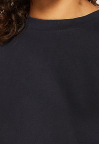 T-shirt en coton bleu marine avec un col rond et une texture côtelée, doté d'une finition élastique autour du col.