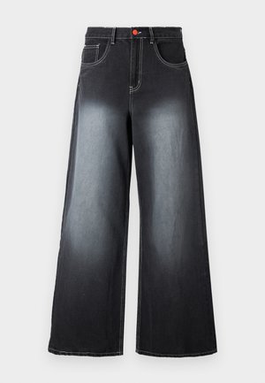 Jean noir à jambes larges avec un avant délavé, des coutures contrastantes blanches, cinq poches et un bouton rouge à la taille.