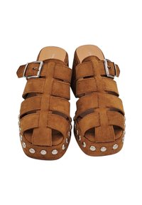 Mules en suède marron à plateforme avec un design à lanières, dotés d'une boucle en argent et de clous métalliques le long de la semelle. Forme à bout carré.