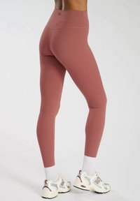 Getextureerde, hooggesneden leggings in een mauve kleur, met een aansluitend ontwerp en contrasterende stiksels. Draag ze met witte sokken en grijze sneakers.