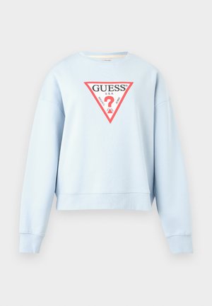 Šviesiai mėlynas ilgomis rankovėmis trumpas džemperis su raudonos ir baltos spalvos trikampiu GUESS logotipu bei užrašu „Washed Jeans“ priekyje centre.