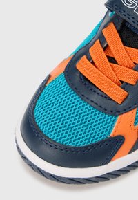 Sportschuh mit türkisem Mesh-Obermaterial, orangefarbenen Akzenten, dunkelblauen Lederdetails, flachen Schnürsenkeln und einer strukturierten Gummisohle.