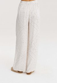 Kalhoty s širokými nohavicemi z lehké látky s jemným vzorem bandany. Elastický pas a manžety; mají měkký, strukturovaný povrch.