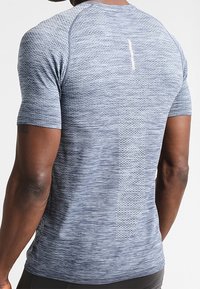 Kortärmad träningsskjorta i strukturert mörkblått tyg med en ljusblå accentdetalj och ett vertikalt ränder på ryggen.