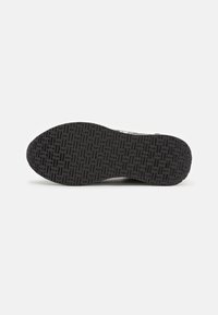 Suola di sneaker nera in gomma testurizzata con grip a motivo. Forma arrotondata con una leggera curvatura sul tallone.