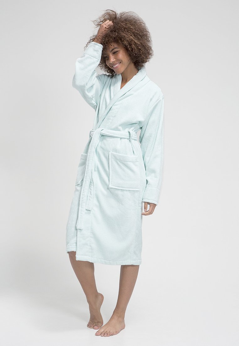 Peignoir de bain en terry bleu clair, doux, avec des manches longues, ceinture à l'avant et deux grandes poches plaquées. Il présente un col châle et une coupe décontractée.