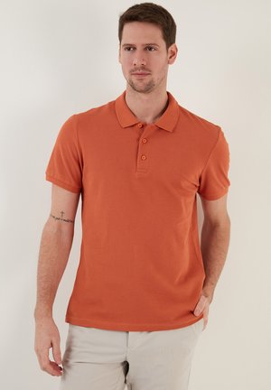 Camisa polo naranja de algodón, con cuello, mangas cortas y tapeta de tres botones. Textura suave con un diseño ajustado.