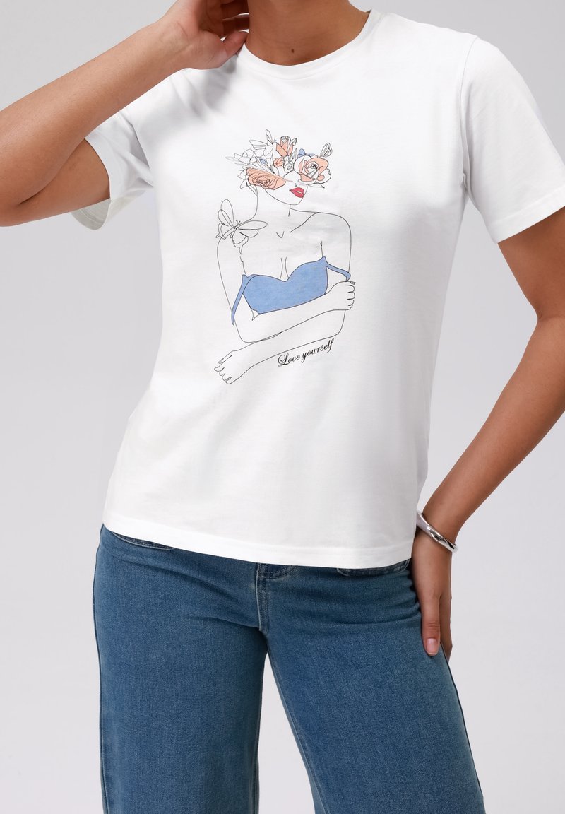 Bílý bavlněný tričko s grafickou ilustrací ženy s květinovými akcenty a nápisem "Miluj sebe" v černé barvě. Krátké rukávy.