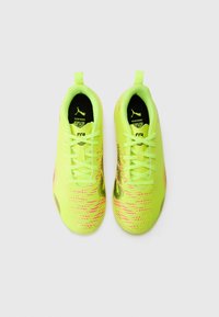 Scarpe da atletica di un vivace giallo con una superficie texturizzata, impreziosite da motivi rosa e neri, e lacci verdi. Design leggero e affusolato.