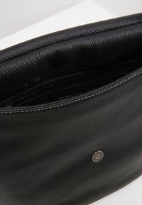 Borsa a mano in pelle nera con finitura texturizzata, chiusura superiore a zip e chiusura metallica a scatto. Presenta un interno foderato con il nome del marchio visibile.