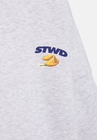 Hanorac gri cu logo albastru „STWD” și un biscuițel norocos galben brodat pe fundal alb, inscripționat cu „CONTINUĂ SĂ ÎNCEARCI”.