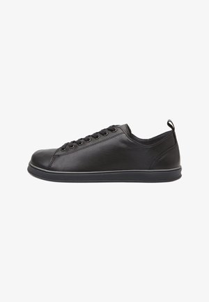 Sneaker basso in pelle nera con chiusura con lacci e linguetta nel tallone, mostrato dal lato interno su sfondo bianco.
