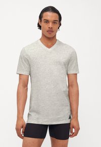 Helles Grau, kurzärmliges V-Neck-T-Shirt aus weichem Stoff. Verfügt über eine subtile Textur und drei schwarze Akzentstreifen nahe dem Saum.