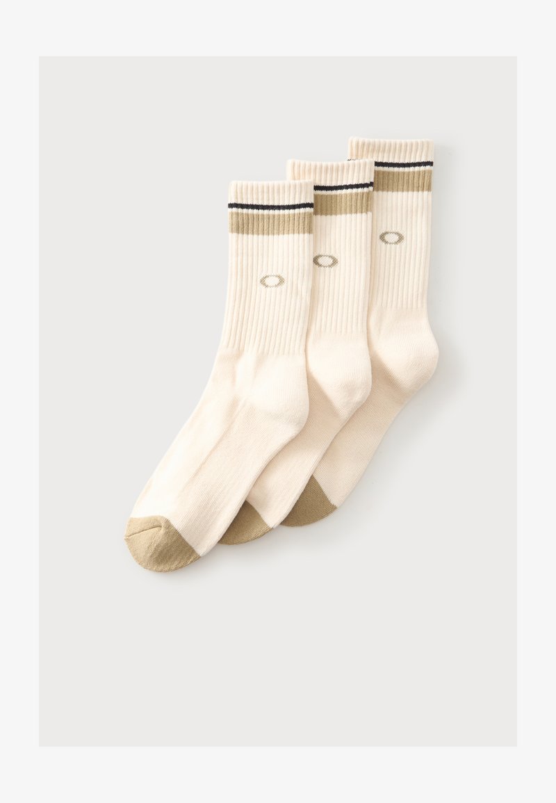 Trois paires de chaussettes côtelées couleur crème avec des accents beiges aux orteils et au talon, ainsi qu'une bande beige et noire près du haut.