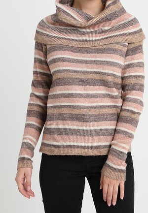 Femme portant un pull en maille douce avec un large col roulé et des rayures horizontales dans des tons de rose, marron, beige et blanc, associé à un pantalon noir.