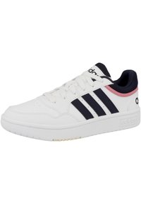 Zapatilla deportiva blanca hecha de cuero sintético, con acentos en azul marino y rosa, tres franjas negras y una suela de goma texturizada.