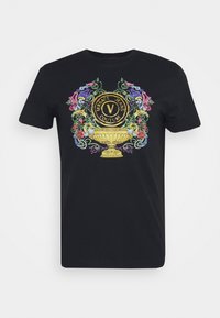 Musta puuvillapaita, jossa on värikäs brodeerattu graafinen kuva koristeellisesta urnasta ja teksti "VERSACE JEANS COUTURE." pyöreä pääntie ja lyhyet hihat.