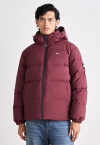 Maroon puffer jacket with a zippered front, elastic cuffs, and a hood. The fabric has a smooth finish with a lightweight, insulated design.