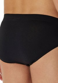 Zwarte katoenen slips met een gladde textuur en een elastische tailleband, zonder zichtbare patronen of accenten. Sluit nauw aan op het lichaam.