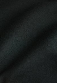 Schwarzer Stoff mit einer glatten, strukturierten Oberfläche, die einen subtilen Glanz und Falten zeigt und das Licht in unterschiedlichen Schattierungen von Dunkel einfängt.