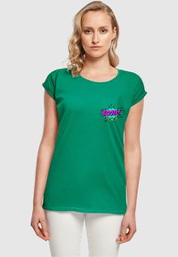 Grøn bomulds t-shirt med rullede ærmer, der har et komik-stil "BOOM!" grafik i pink og sort på venstre brystområde.