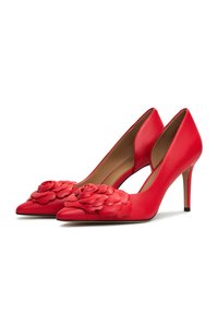 Pantofi cu toc înalt din piele roșie, cu vârf ascuțit, prezentând decorațiuni florale stratificate în față și toc stiletto.