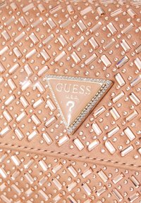 Clutch-veske i rosagull med teksturert overflate, prydet med rektangulære og runde metallnagl, samt en glitrende logo-plakett.