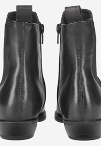 Bottines en cuir noir avec une texture lisse, des zips sur le côté et des bouts ronds, dotées d'un petit talon empilé et de détails de couture minimalistes.