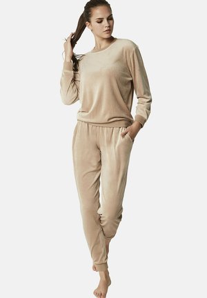 Beige loungewear-set van zacht, fluwelen stof. Het topje heeft lange mouwen en een elastische rand; de broek heeft een elastische tailleband en zakken.