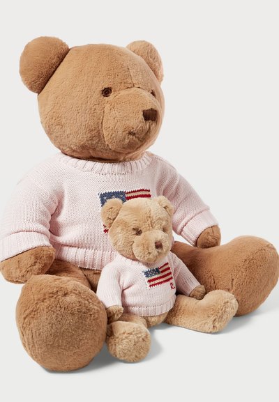 Dos osos de peluche sentados juntos. El oso más grande es de color marrón claro y lleva un suéter rosa con un diseño de bandera. El oso más pequeño lleva un suéter a juego.