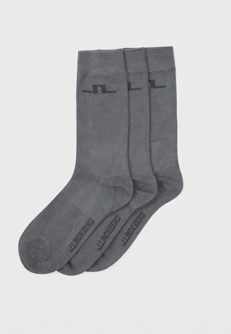 Τρία ζευγάρια σκουρόχρωμες γκρι κάλτσες μήκους  μέχρι τη μέση της γάμπας με ριμπ μανσέτες και διακριτικό λογότυπο κοντά στα δάχτυλα και στις επάνω μανσέτες, εμφανίζονται σε λευκό φόντο.