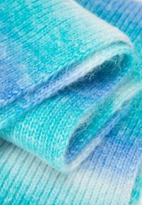 Tessuto lavorato a maglia in sfumature degradanti di turchese e azzurro chiaro. Texture morbida con fibre visibili e finitura liscia. Piegato e sovrapposto.