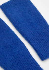 Blaue Woll-Armtaschen mit einer weichen, strukturierten Oberfläche. Rippendetails oben verbessern die Struktur. Keine sichtbaren Metallteile oder Verzierungen.