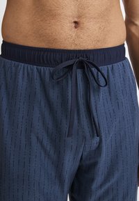 Marineblauwe shorts met een gestructureerd patroon van smalle verticale lijnen. Voorzien van een elastische tailleband met een trekkoord voor een verstelbare pasvorm.