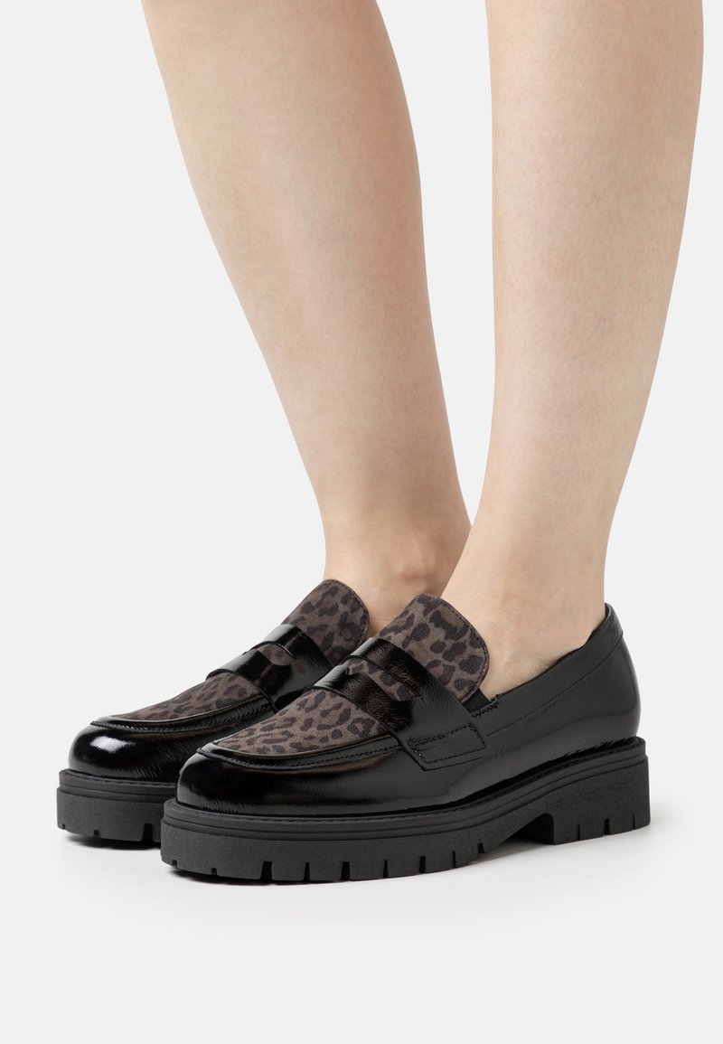 Mocassins en cuir verni noir avec un panneau à imprimé léopard texturé, dotés d'une semelle épaisse et de lanières décoratives traversant le cou-de-pied.