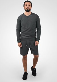 Dark gray sweatshirt with a round neckline, textured fabric, and cuffs. Paired with matching dark gray shorts featuring an elastic waistband.