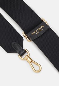 Sangle en tissu noir avec texture striée, dotée d'un clip en métal couleur or et d'une étiquette en cuir noir embossée avec "kate spade NEW YORK."