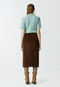 Svijetloplava kratka majica s kratkim rukavima, prilagođena. Smeđa korduroy midi suknja, teksturirana, s stražnjim džepovima. Bež antilop gležnjače sa trakama.