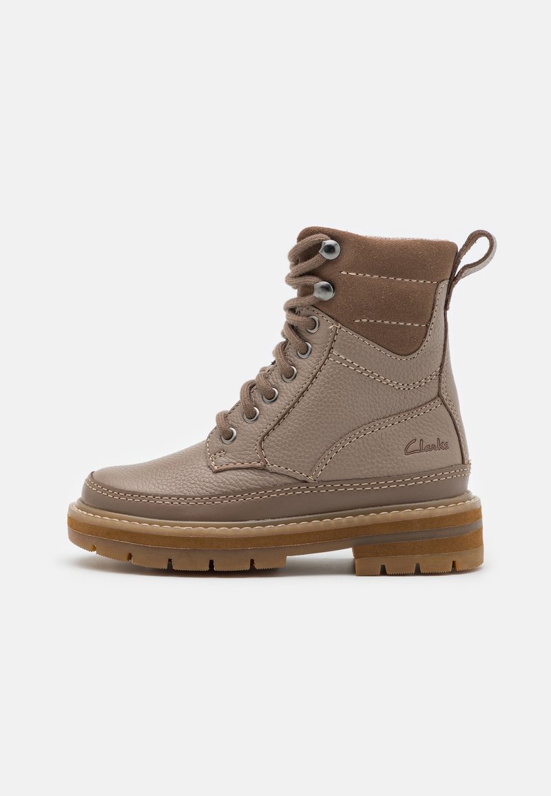 Bottine en cuir marron à lacets avec col rembourré, semelle épaisse en caoutchouc et languette au talon, affichant le logo Clarks sur le côté.