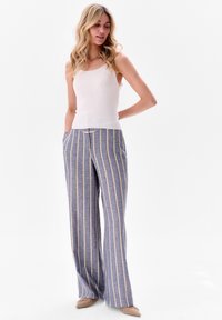 Brede blauwe gestreepte broek met gele strepen, gemaakt van lichtgewicht stof. Gecombineerd met een aansluitend licht tanktop.