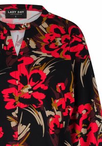 Bloemenblouse van zwarte stof, met opvallende rode en beige bloemenpatronen, korte mouwen, een hoge halslijn en een kleine metallic accenten.